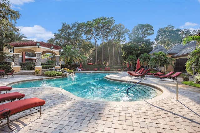 view of swimming pool with pool water feature and a patio area