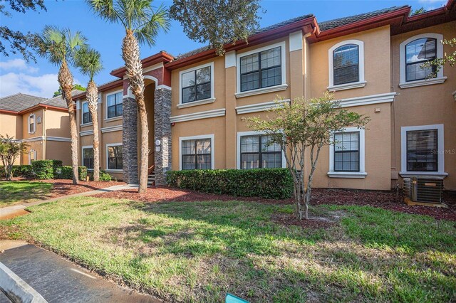 view of front of property with central AC unit and a front lawn