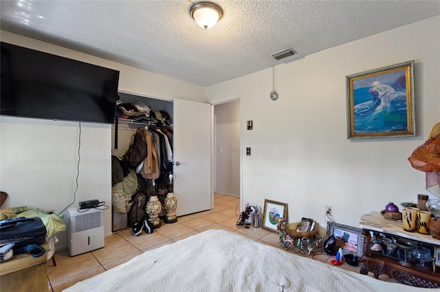 bedroom featuring a closet, a textured ceiling, and light tile patterned floors