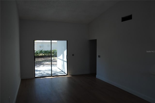 spare room with wood finished floors, lofted ceiling, and baseboards
