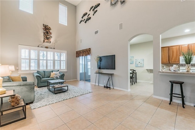 living room with light tile patterned floors and a high ceiling