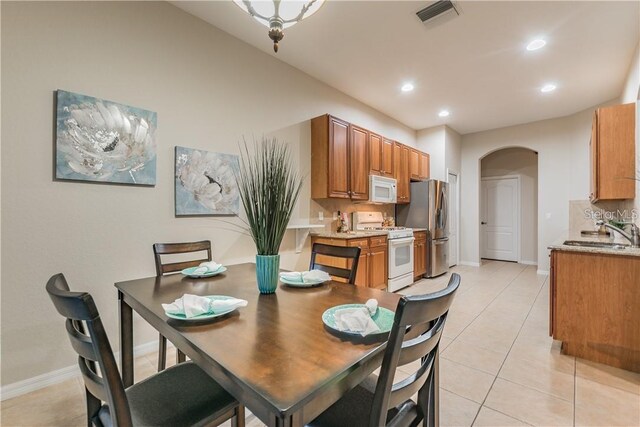 dining space with light tile patterned floors, visible vents, arched walkways, baseboards, and recessed lighting
