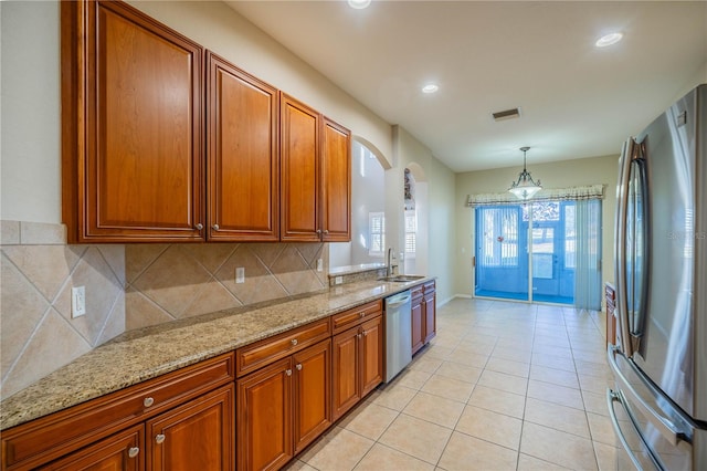 kitchen featuring light stone countertops, stainless steel appliances, sink, pendant lighting, and light tile patterned flooring