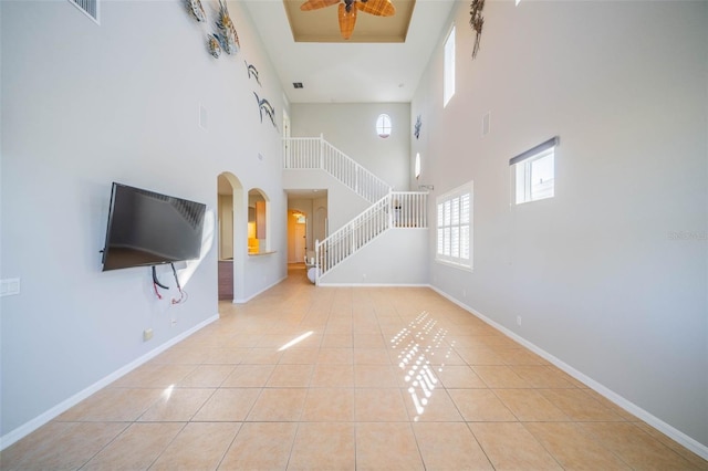 unfurnished living room with tile patterned flooring, baseboards, and stairs