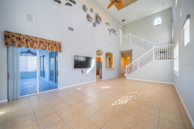 unfurnished living room featuring stairs, visible vents, a ceiling fan, and tile patterned floors