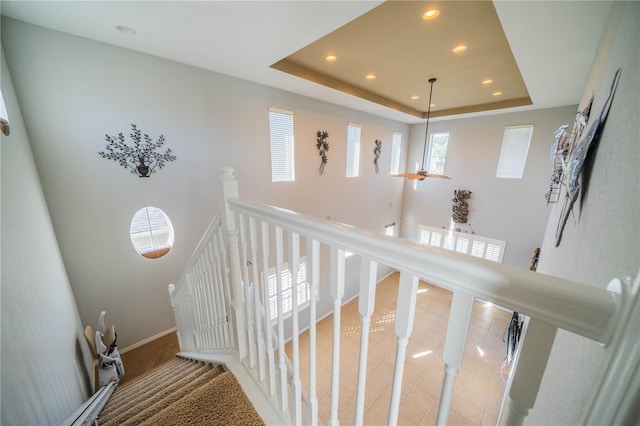 staircase with baseboards, a raised ceiling, and recessed lighting
