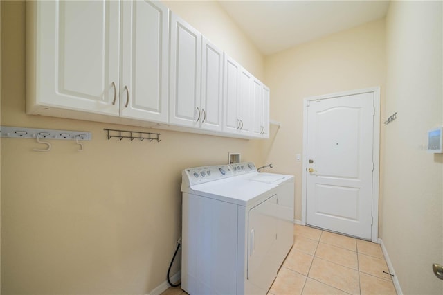 clothes washing area with light tile patterned floors, cabinet space, baseboards, and separate washer and dryer