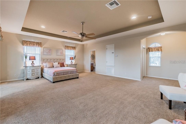bedroom with visible vents, a raised ceiling, and arched walkways