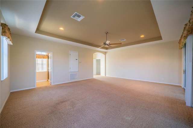 carpeted empty room with a tray ceiling and ceiling fan