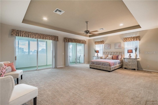 carpeted bedroom with access to exterior, a tray ceiling, and ceiling fan