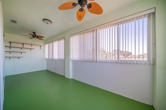 unfurnished sunroom with a healthy amount of sunlight, ceiling fan, and visible vents