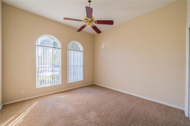 spare room featuring a ceiling fan, carpet, and baseboards