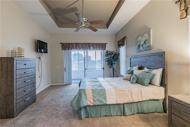carpeted bedroom featuring access to outside, baseboards, a raised ceiling, and a ceiling fan