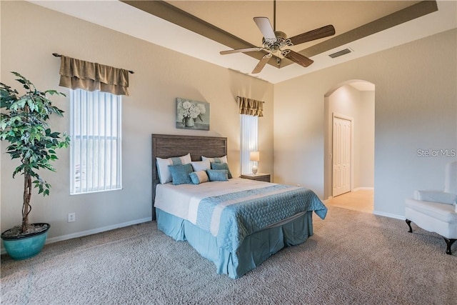 carpeted bedroom featuring a ceiling fan, arched walkways, visible vents, and baseboards