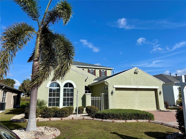 view of front of home with a garage, a front yard, and central AC