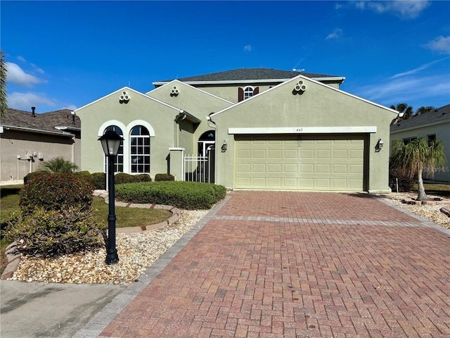 ranch-style house featuring decorative driveway, an attached garage, and stucco siding