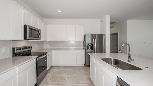 kitchen featuring appliances with stainless steel finishes, sink, light tile patterned floors, and white cabinets