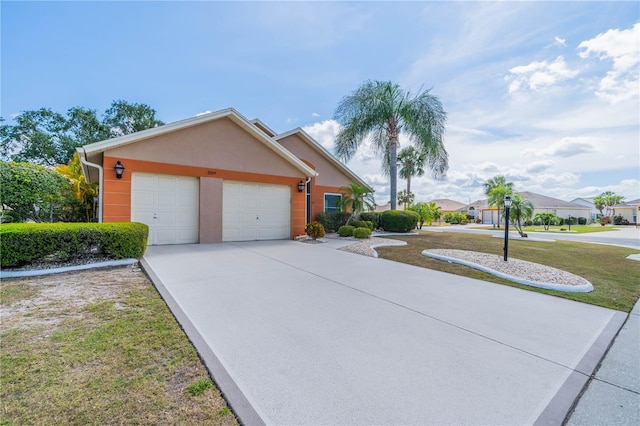 view of front of property with concrete driveway, a front yard, an attached garage, and stucco siding