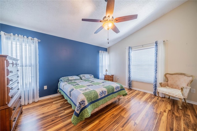 bedroom featuring ceiling fan, hardwood / wood-style flooring, lofted ceiling, and multiple windows