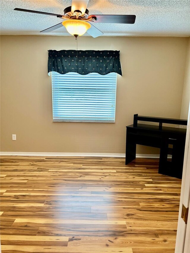 interior space with a textured ceiling, ceiling fan, and hardwood / wood-style flooring