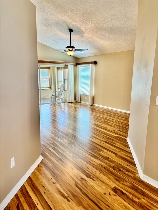 empty room with wood-type flooring, ceiling fan, and a textured ceiling