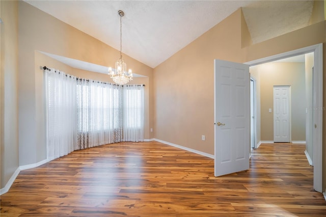 unfurnished dining area featuring high vaulted ceiling, wood-type flooring, and a chandelier