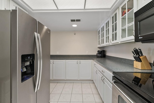 kitchen with appliances with stainless steel finishes, light tile patterned flooring, and white cabinets