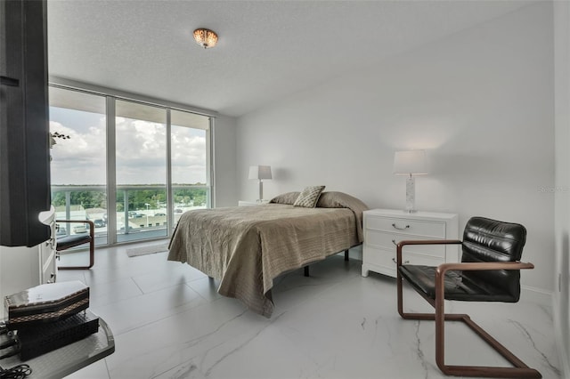 bedroom featuring access to exterior, expansive windows, and a textured ceiling