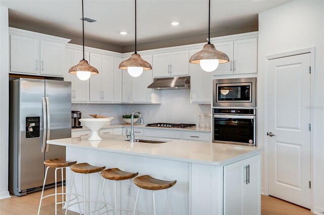 kitchen featuring stainless steel appliances, tasteful backsplash, sink, light wood-type flooring, and white cabinets