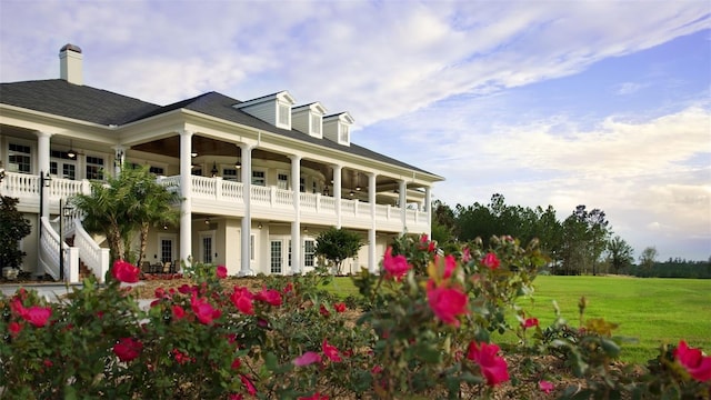 rear view of house featuring a lawn and a balcony