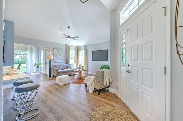 living room with a healthy amount of sunlight, ceiling fan, vaulted ceiling, and light hardwood / wood-style floors