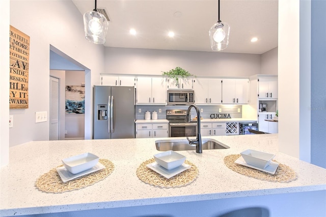 kitchen with appliances with stainless steel finishes, sink, backsplash, white cabinetry, and hanging light fixtures