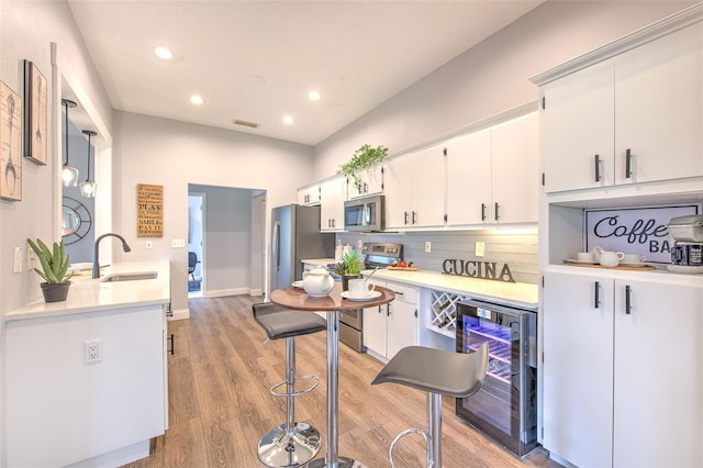 kitchen featuring white cabinetry, stainless steel appliances, hanging light fixtures, wine cooler, and sink