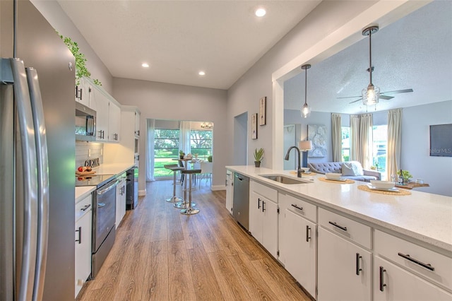 kitchen featuring sink, white cabinetry, decorative light fixtures, light hardwood / wood-style floors, and stainless steel appliances