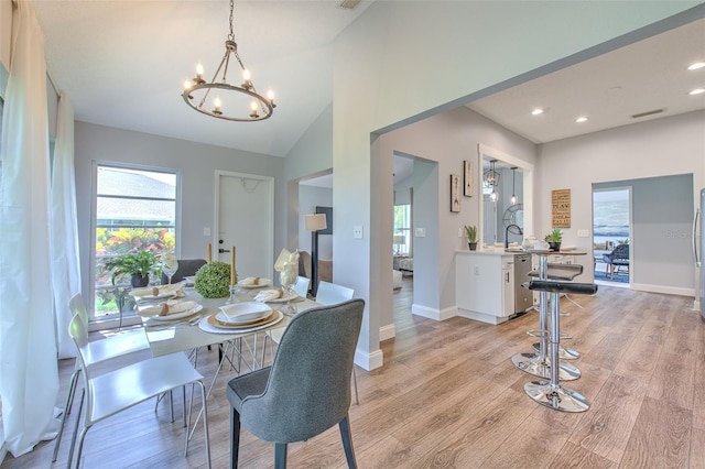 dining room with a notable chandelier, light hardwood / wood-style floors, and lofted ceiling