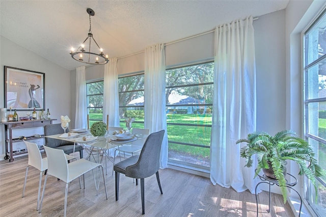 dining area with hardwood / wood-style flooring, vaulted ceiling, a textured ceiling, and a notable chandelier