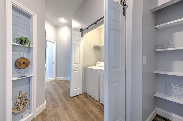 laundry room featuring a barn door, light hardwood / wood-style flooring, a textured ceiling, and washer / dryer