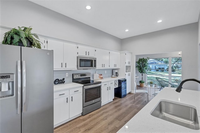 2309 Mooney Pl, Sun City Center, FL 33573 - kitchen with appliances with stainless steel finishes, tasteful backsplash, a sink, white cabinets, and recessed lighting
