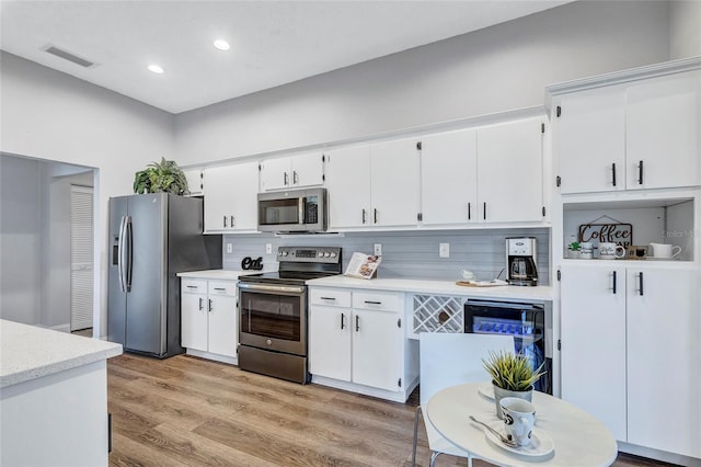 2309 Mooney Pl, Sun City Center, FL 33573 - kitchen with visible vents, decorative backsplash, light countertops, white cabinets, and stainless steel appliances