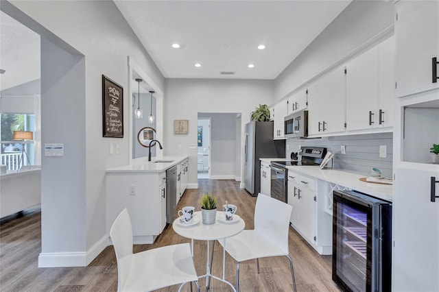 2309 Mooney Pl, Sun City Center, FL 33573 - kitchen with stainless steel appliances, light wood-style floors, a sink, and wine cooler