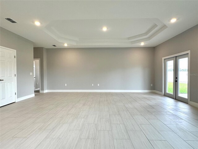 unfurnished room featuring a raised ceiling and french doors