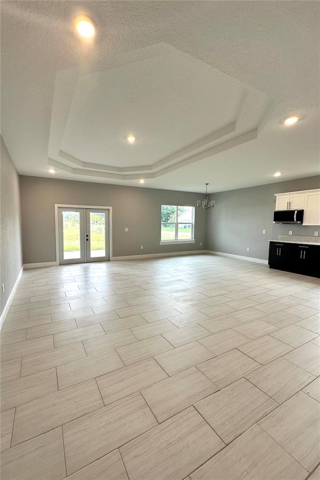 unfurnished living room with a tray ceiling, a healthy amount of sunlight, and light tile patterned floors