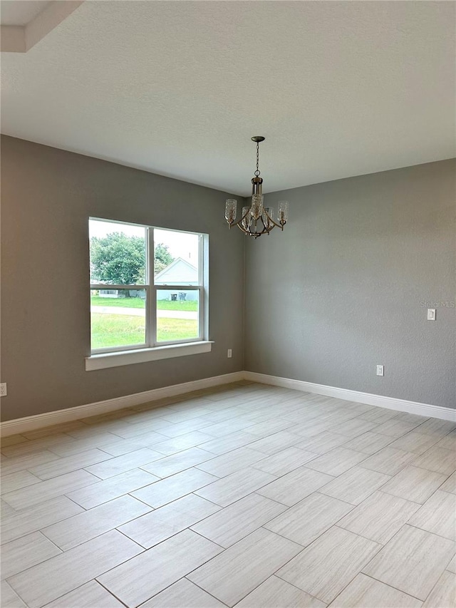 tiled spare room with a chandelier