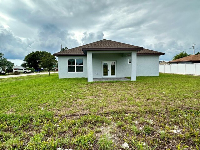 rear view of property featuring a lawn and french doors