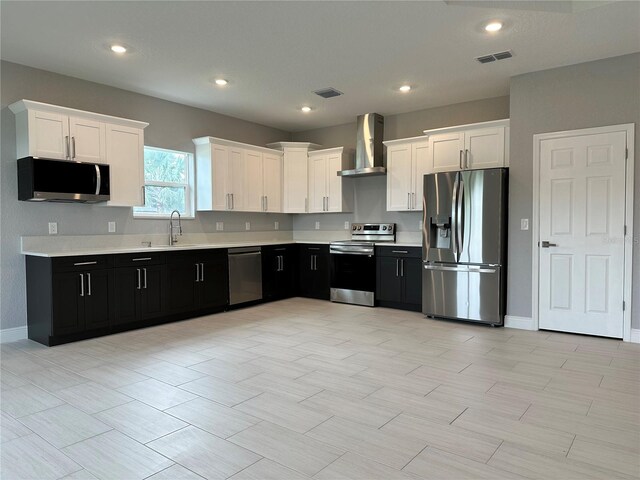 kitchen featuring sink, stainless steel appliances, wall chimney range hood, and white cabinets