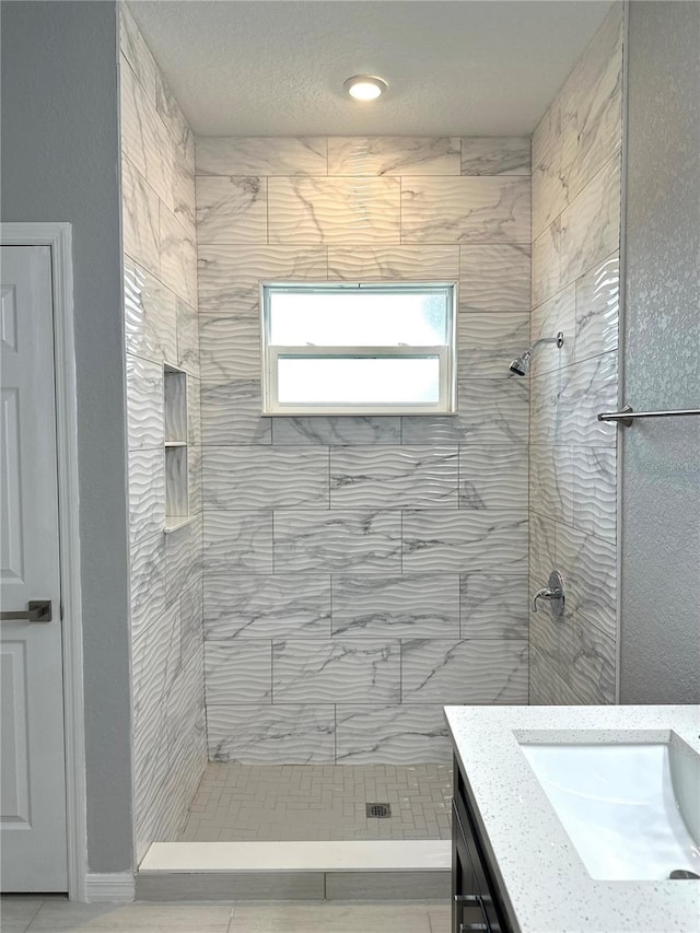 bathroom with tiled shower, vanity, and tile patterned floors