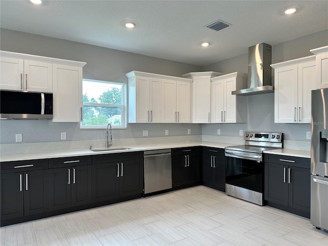 kitchen featuring appliances with stainless steel finishes, white cabinetry, sink, wall chimney range hood, and light tile patterned floors