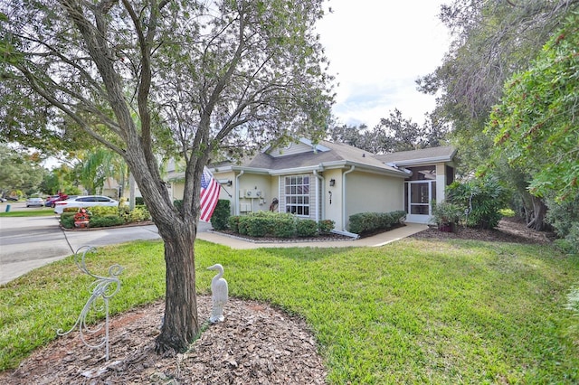 view of front of house with a front yard, concrete driveway, and stucco siding