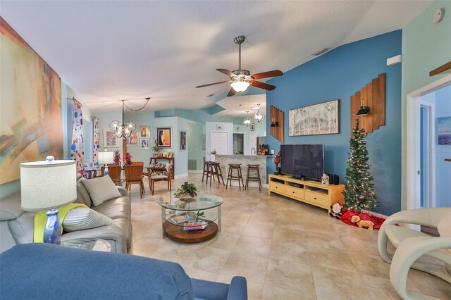 living room featuring ceiling fan with notable chandelier and vaulted ceiling