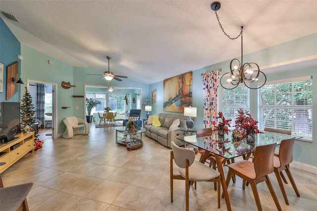 tiled dining room featuring lofted ceiling, ceiling fan with notable chandelier, and a textured ceiling